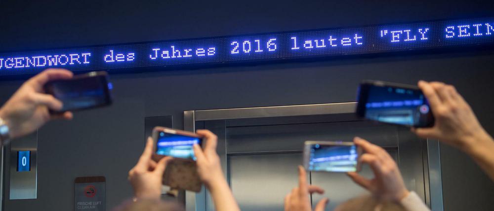 Die Worte "Fly sein" flimmern als "Jugendwort des Jahres" über den digitalen Newsticker eines Hotels in München.