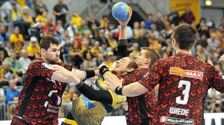 Ringen um den Handball. Jakov Gojun (l) und Bjarki Elisson (2.v.r) von den Füchsen im Kampf um den Ball mit Kim Ekdahl du Rietz von den Löwen. 