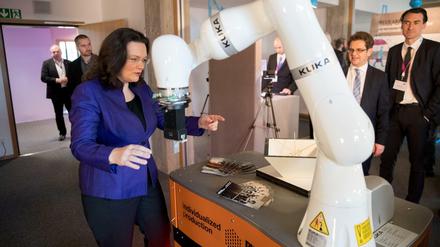 Bundesarbeitsministerin Andrea Nahles (SPD) steht am 29.11.2016 in Berlin in einer Ausstellung zur Arbeitswelt 4.0 an einem Roboterarm der Firma Kuka. 