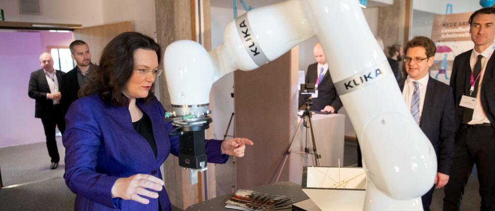 Bundesarbeitsministerin Andrea Nahles (SPD) steht am 29.11.2016 in Berlin in einer Ausstellung zur Arbeitswelt 4.0 an einem Roboterarm der Firma Kuka.