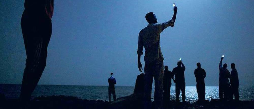 Auf Kontaktsuche: Afrikanische Flüchtlinge versuchen am Strand von Dschibuti ein Handysignal zu empfangen, um ihre Verwandten in der Heimat zu erreichen. 2014 erhielt der Fotograf John Stanmeyer für diese Aufnahme den renommierten World Press Photo Award.
