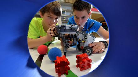 Zwei Schüler bauen einen technischen Apparat aus Legosteinen.