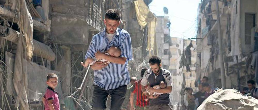Das nackte Leben. Nach einem Bombenangriff versuchen Männer in Aleppo, Säuglinge in Sicherheit zu bringen.