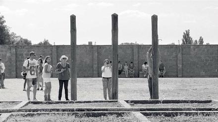 Meditation im Menschenzoo. KZ-Besucher fotografieren sich an Pfählen, wo Häftlinge damals die Arme gebrochen wurden.