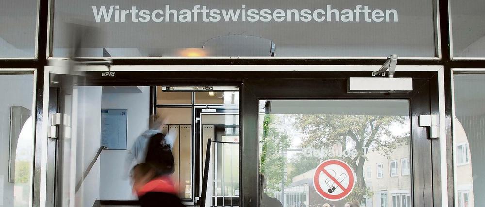 Ein Student betritt ein Unigebäude mit der Aufschrift Wirtschaftswissenschaften.