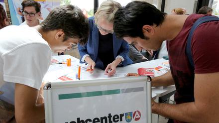 Auf einer Ausbildungsmesse für Flüchtlinge hilft Ulrike Nennhaus (M) vom Jobcenter Schwerin beim Ausfüllen von Formularen. 