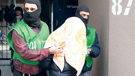 Polizisten führen bei einer Razzia gegen Islamisten am 04.02.2016 in Berlin einen mit einem Tuch verdeckten Verdächtigen ab. 