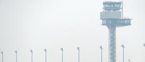 Eine Gruppe von Rehen springen vor der Kulisse des Towers auf dem neuen Hauptstadtflughafen BER in Schönefeld auf einem Feld. 