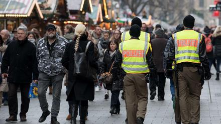 Polizisten gehen über einen Weihnachtsmarkt. 