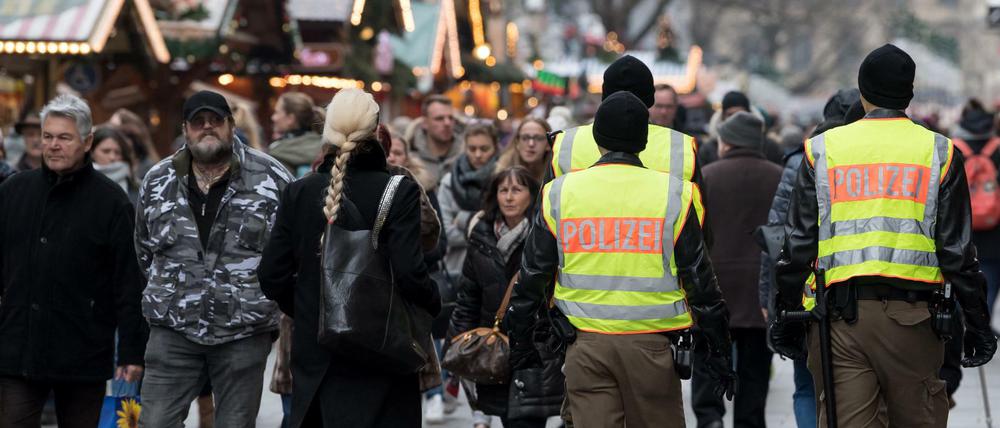 Polizisten gehen über einen Weihnachtsmarkt. 