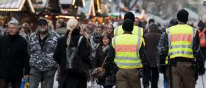 Polizisten gehen über einen Weihnachtsmarkt. 