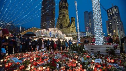 Zahlreiche Menschen stehen am 22.12.2016 um die Blumen und Kerzen, die am Weihnachtsmarkt am Breitscheidplatz in Berlin abgelegt wurden. 