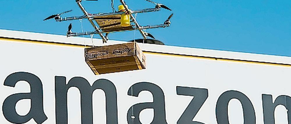 Eine Drohne mit einem Amazon-Paket schwebt vor dem Amazon Logistikzentrum Leipzig.