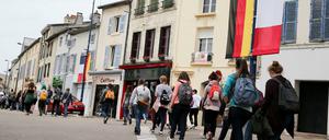 Jugendliche gehen eine Straße herunter, die mit deutschen und französischen Flaggen geschmückt ist.