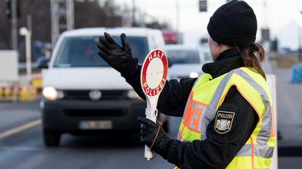 Ein Polizistin winkt an einer Kontrollstelle Fahrzeuge, die aus Österreich kommen, für eine Kontrolle aus dem Verkehr.