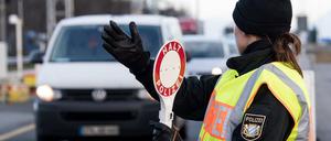 Ein Polizistin winkt an einer Kontrollstelle Fahrzeuge, die aus Österreich kommen, für eine Kontrolle aus dem Verkehr.