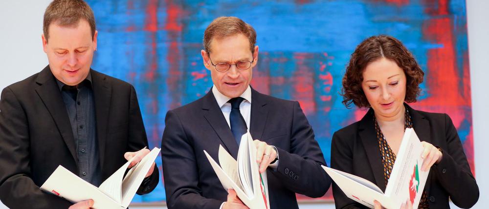 Da steht's: Seite 172 des rot-rot-grünen Koalitionsvertrags, Abschnitt IV: „Gutes Regieren in Berlin“. Hier blättern Klaus Lederer, Michael Müller und Ramona Pop (v.l.) im eigenen Auftragswerk.