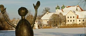 Eine Skulptur steht vor der Kulisse des Klosters Seeon