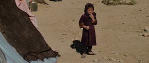 A girl stands next to tents at a temporary camp near a highway between Herat and Badghis on October 14, 2021. (Photo by Hoshang Hashimi / AFP)