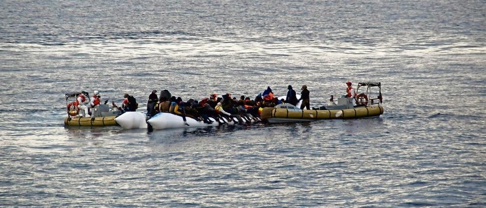 Rettung aus Seenot. Italienische Marinesoldaten helfen Flüchtlingen vor der Küste Siziliens.