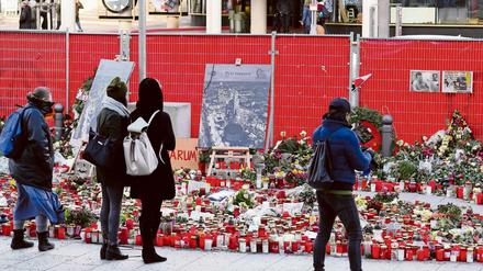 Menschen bleiben vor Kerzen und Blumen stehen, um der Opfer des Anschlags auf den Weihnachtsmarkt am Breitscheidplatz zu gedenken.