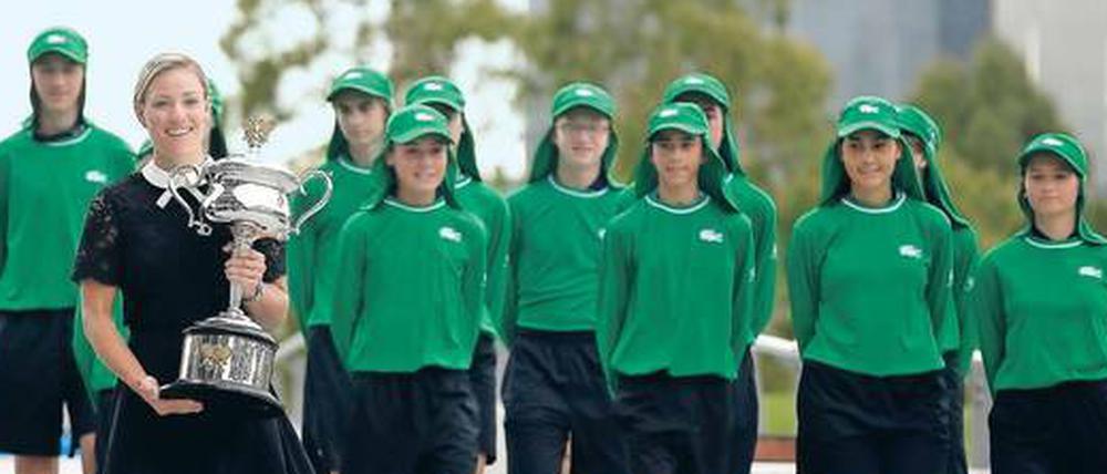 Im Stile einer Klosterschülerin. In schwarzem Spitzenkleid trug Titelverteidigerin Kerber den Siegerpokal über den Garden Square vor der Rod Laver Arena. 
