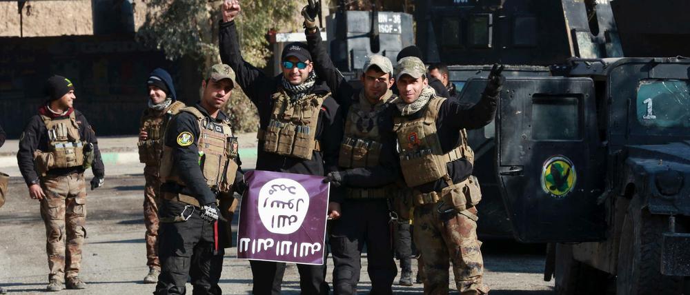 Irakische Spezialkräfte posieren Mitte Januar mit einer Fahne des "IS" in einem Nachbarort von Mossul. Das Ostufer der nordirakischen Stadt sei nach Aussagen des US-Militärs bereits zu 90 Prozent unter Kontrolle.