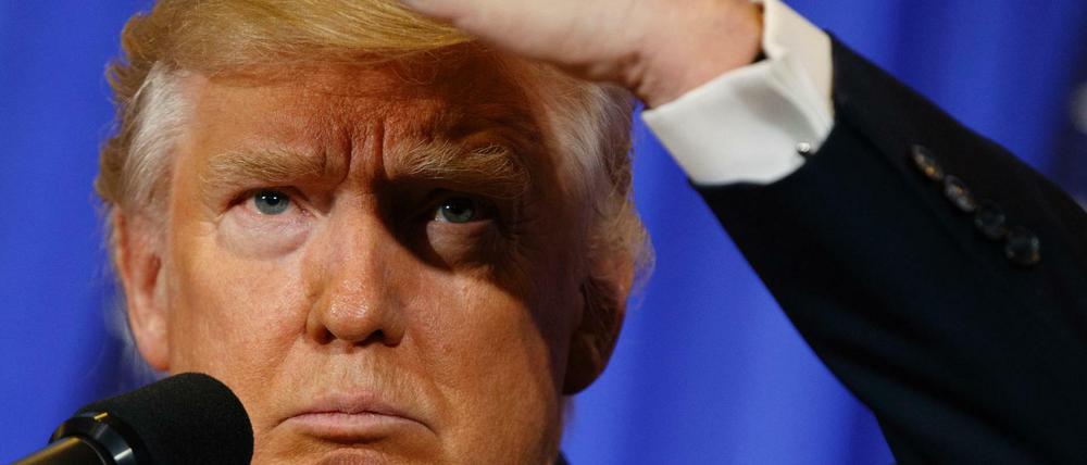 Donald Trump schirmt seine Augen mit der Hand ab, um trotz der blendenden Scheinwerfer sehen zu können. 