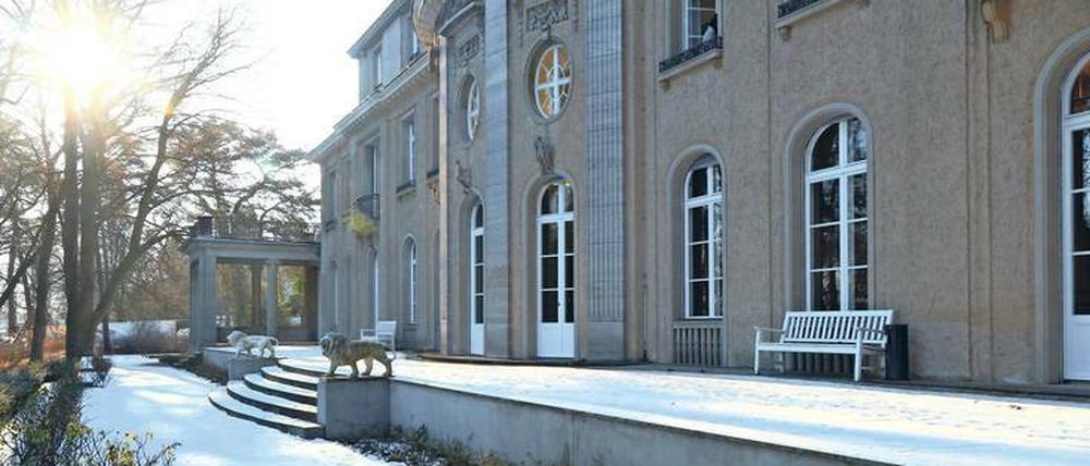 Die Fassade einer Villa im Gegenlicht fotografiert, davor schneebedeckte Gartenanlagen.