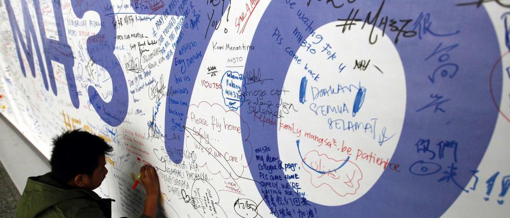 Ein Passagier schreibt am 13.03.2014 eine Nachricht an Passagiere des verschwundenen Malaysia-Airlines-Fluges mit der Flugnummer MH370 auf ein Banner am internationalen Flughafen von Kuala Lumpur, Malaysia.