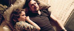 Eine Frau und ein Mann liegen aneinandergeschmiegt auf einem Bett.