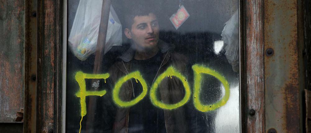 Ein Flüchtling steht an einem Fenster mit der Aufschrift "Food" in einer verlassenen Lagerhalle, die einigen Hunderten Flüchtlingen Schutz bietet, in Belgrad.