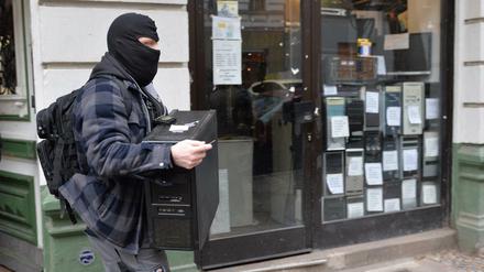 Ein Polizist trägt im Rahmen der bundesweiten Razzia gegen Reichsbürger einen Computer aus einem Haus in Berlin-Moabit. 