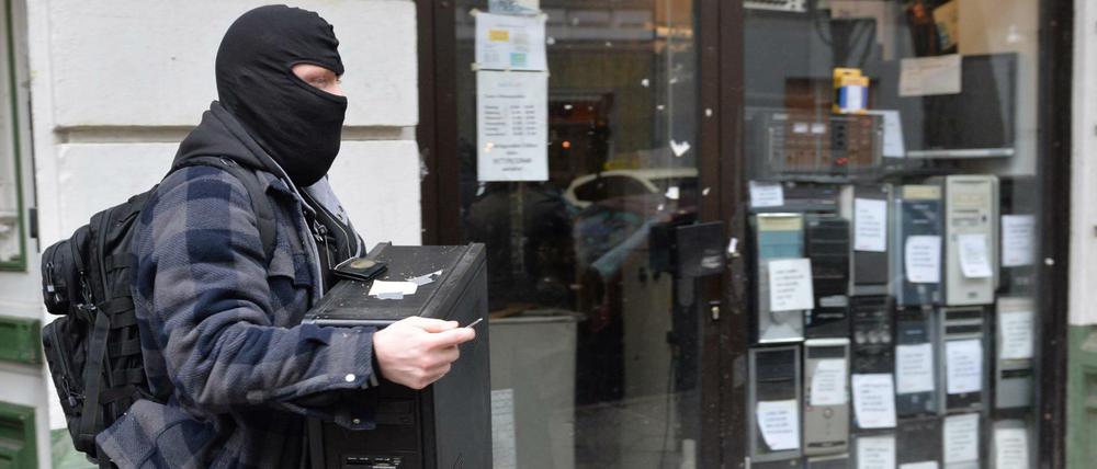 Ein Polizist trägt im Rahmen der bundesweiten Razzia gegen Reichsbürger einen Computer aus einem Haus in Berlin-Moabit.