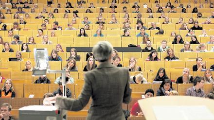 Eine Frau steht an einem Projektor vor Studierenden in einem Hörsaal.