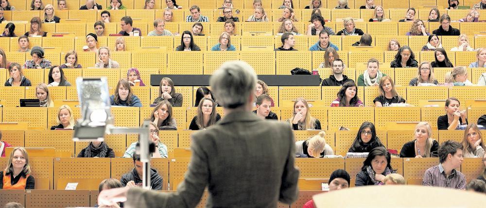 Eine Frau steht an einem Projektor vor Studierenden in einem Hörsaal.