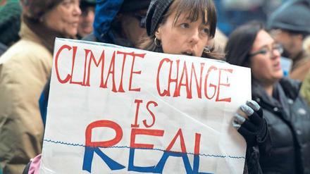 Eine Frau hält ein Schild mit der Aufschrift Climate Change is real in den Händen.