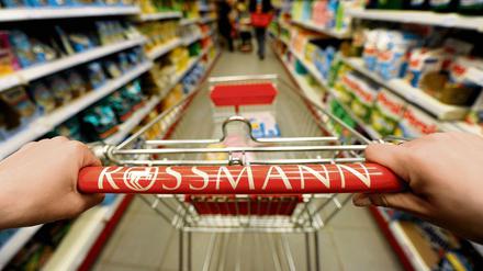 Ein Kundin schiebt in einer Rossmann-Filiale einen Einkaufswagen durch die Gänge.