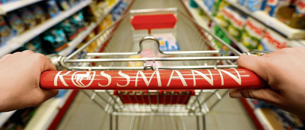 Ein Kundin schiebt in einer Rossmann-Filiale einen Einkaufswagen durch die Gänge.