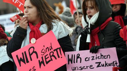 Zwei junge Frauen zeigen beim Streik der Berliner Erzieher und Sozialpädagogen Plakate, die ihren Unmut zum Ausdruck bringen.