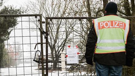 Ein Polizist vor einem abgesperrten, privaten Grundstück in der Nähe von Arnstein (Landkreis Main-Spessart) bei Würzburg. Nach dem Fund von sechs Toten in einer Gartenlaube in Unterfranken ist die Todesursache nun geklärt.