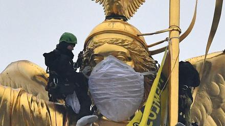Aktivisten der Umweltschutzorganisation Greenpeace haben eine Atemschutzmaske der Statue auf der Siegessäule übergezogen. 