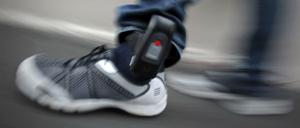 Ein Bewährungshelfer demonstriert ein Modell einer elektronischen Fußfessel. 