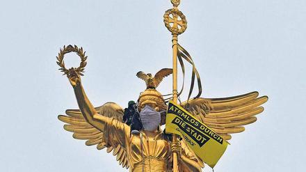 Die Maskenfrau. Aus Protest gegen die anhaltende Luftverschmutzung verhüllten Umweltschützer die Siegessäule. 
