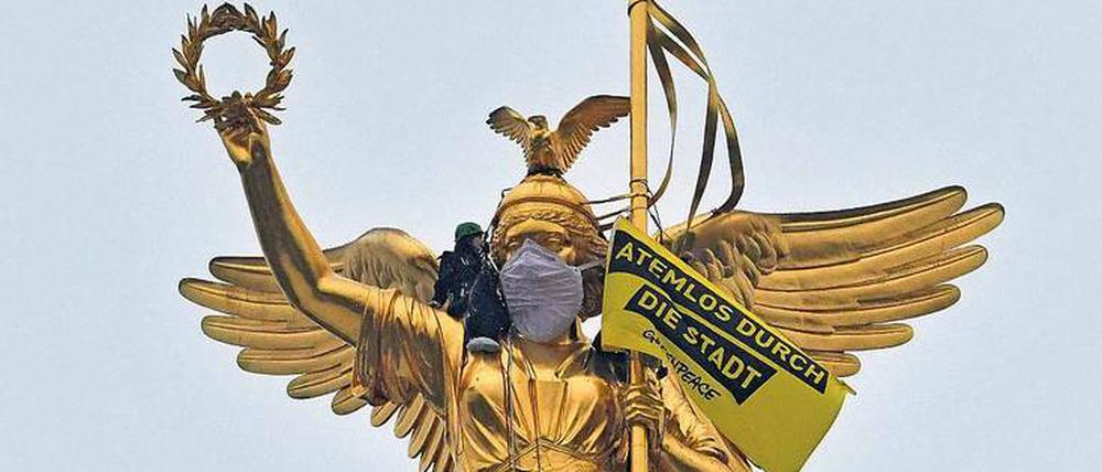 Die Maskenfrau. Aus Protest gegen die anhaltende Luftverschmutzung verhüllten Umweltschützer die Siegessäule.