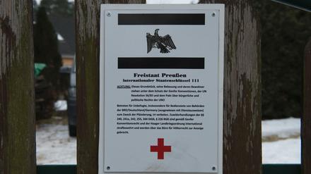 Ein Schild hängt am Grundstückstor vor dem Haus in Cottbus, in dem sogenannte Reichsbürger wohnen. Bei einer Razzia gegen die Reichsbürger wurden in der Stadt verschiedene Räumlichkeiten durchsucht.