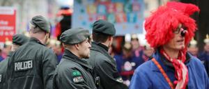 Polizisten stehen in Köln neben Karnevalisten am Zugweg.
