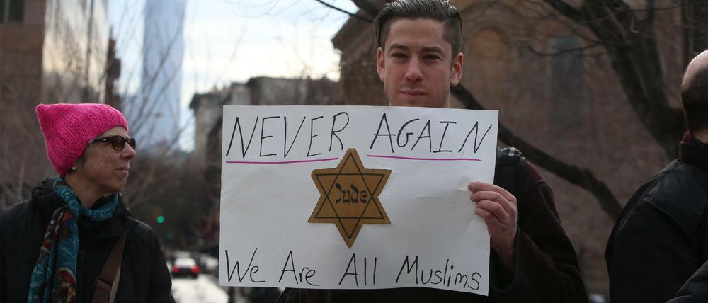 Ein Demonstrant hält bei einem Protest im Washington Square Park in New York ein Plakat mit einem Judenstern und der Aufschrift "Never again - We are all Muslims". Die Demonstration richtete sich gegen US-Präsident Trumps Einreiseverbot, von dem Menschen aus sieben mehrheitlich islamisch geprägten Ländern betroffen waren.