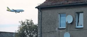 Hier rauscht ein Flugzeug geräuschvoll an einem Wohngebiet vorbei