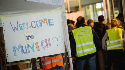 Freiwillige Helfer stehen am 05.09.2015 am Hauptbahnhof in München neben dem Schild "Welcome to Munich". 